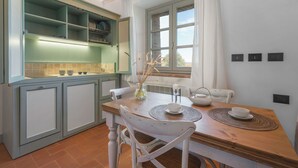 Eine Küche mit Holztisch, weißen Stühlen und einem Fenster mit Vorhängen.