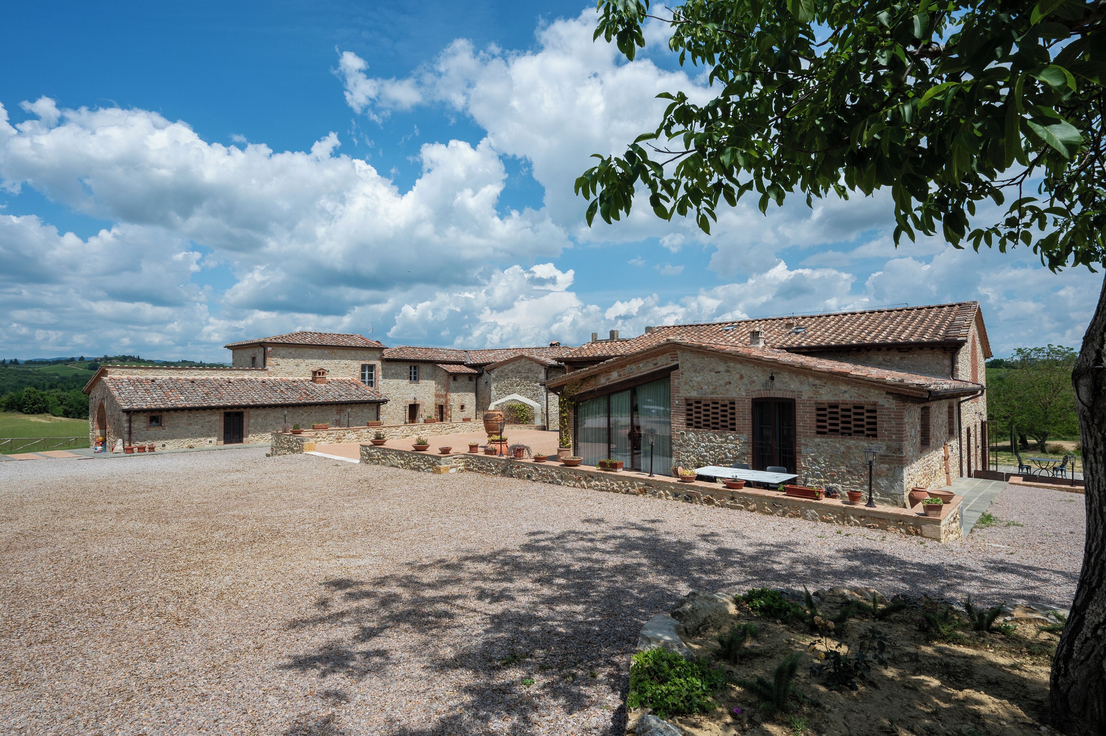 A rustic stone building with a gravel driveway and a patio area.