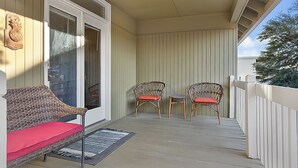 A covered porch with a wicker sofa, two wicker chairs, and a small table.