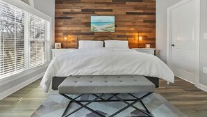 A bedroom with a bed, bench, and wooden wall paneling.