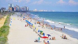 A crowded beach with umbrellas and people.