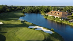 A golf course with a clubhouse adjacent to a lake.