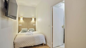 Ein Schlafzimmer mit einem Bett, zwei Wandlampen, einem Fernseher und einer Tür.