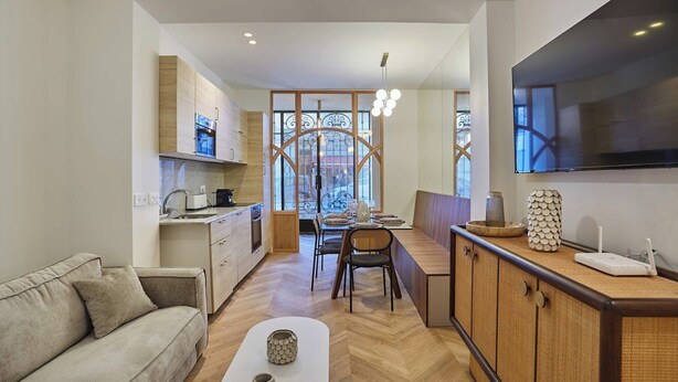Eine moderne Küche mit Holzschränken, ein Essbereich mit Tisch und Stühlen sowie eine Sitzecke mit Sofa.