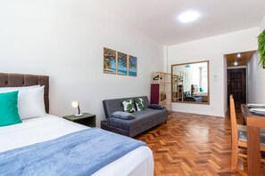 Un dormitorio con cama, sofá, mesita de noche y espejo.