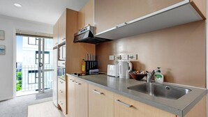 Une cuisine moderne dotée d’un évier en acier inoxydable, de meubles en bois et d’une hotte intégrée.