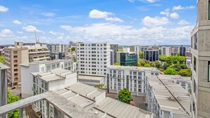 Un quartier urbain caractérisé par de grands immeubles, un ciel dégagé et quelques espaces verts.