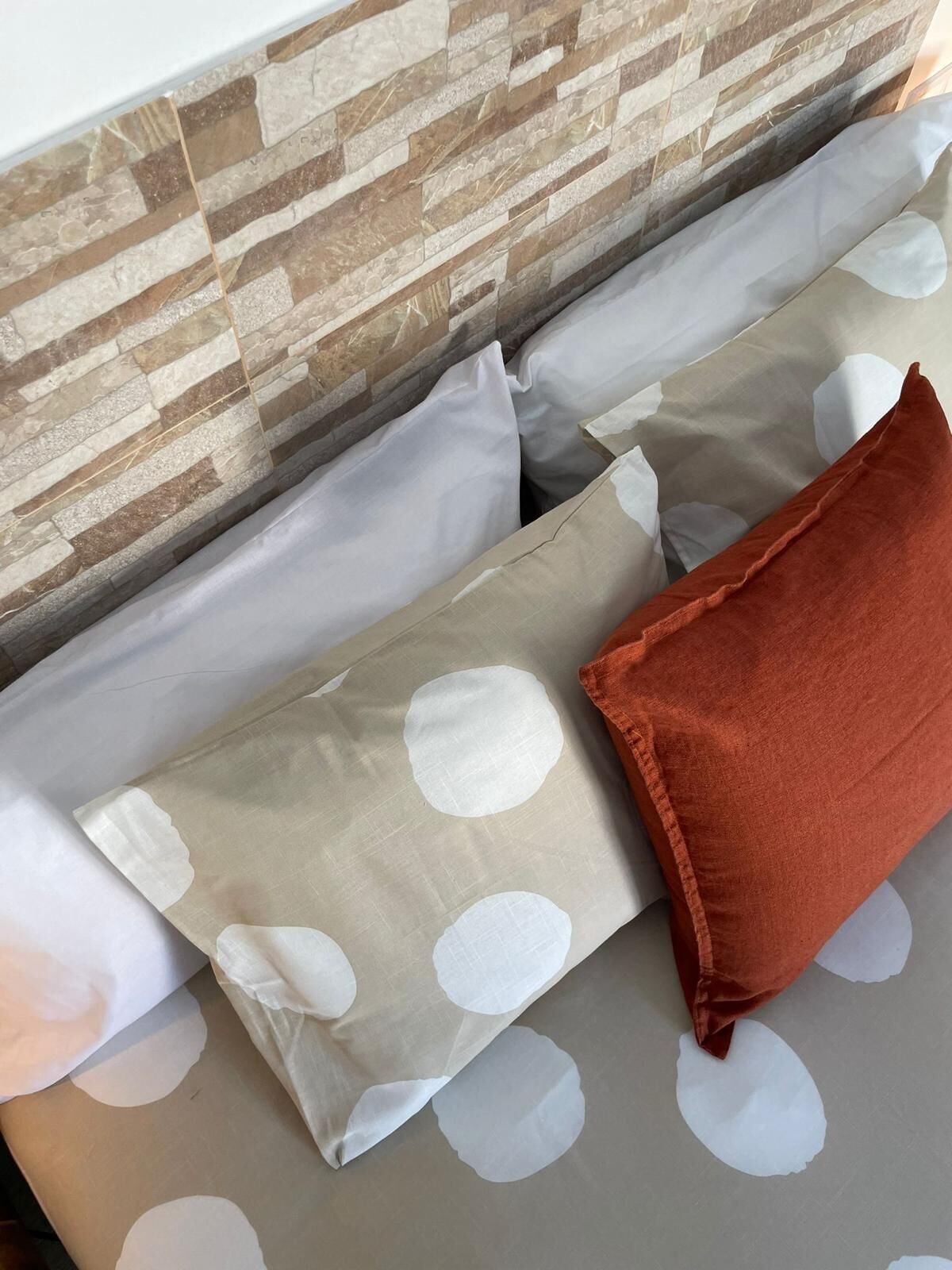 A bed with a patterned pillow and a solid-colored pillow.