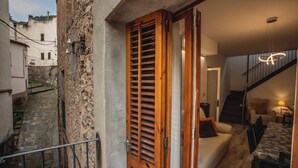 Un estrecho callejón de piedra que conduce a una puerta de madera, una escalera y una sala de estar acogedora con un sofá y una mesa.