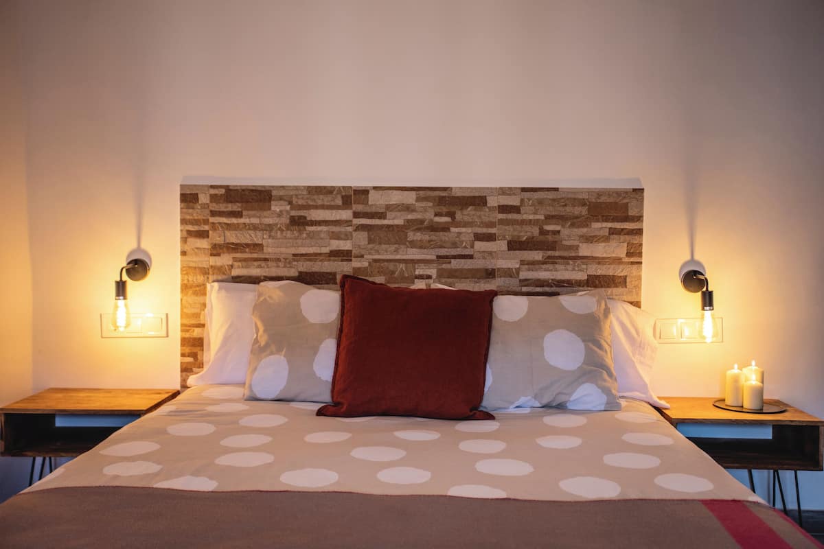 A neatly made bed with a polka dot bedspread, a wooden headboard, and two bedside lamps.