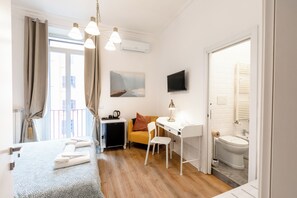 A compact hotel room with a bed, a desk, a chair, a TV, and a bathroom. - Rome Lux House guest rooms (Rome)