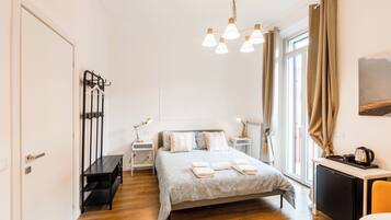 Un dormitorio moderno con cama, mesitas de noche, escritorio y una lámpara colgante.