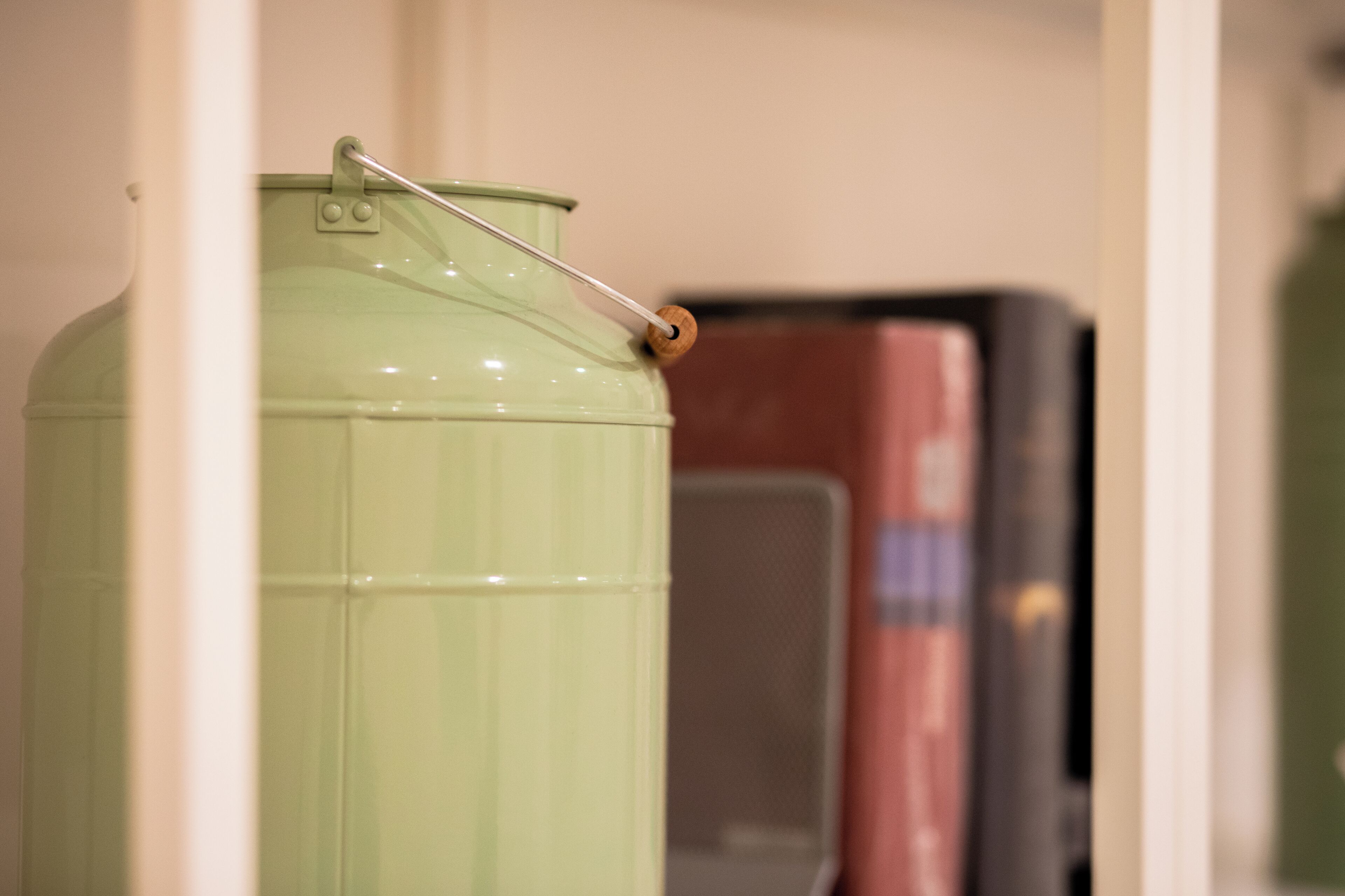 Un contenedor verde con asa metálica y pomo de madera, probablemente un objeto de almacenamiento o utilidad.