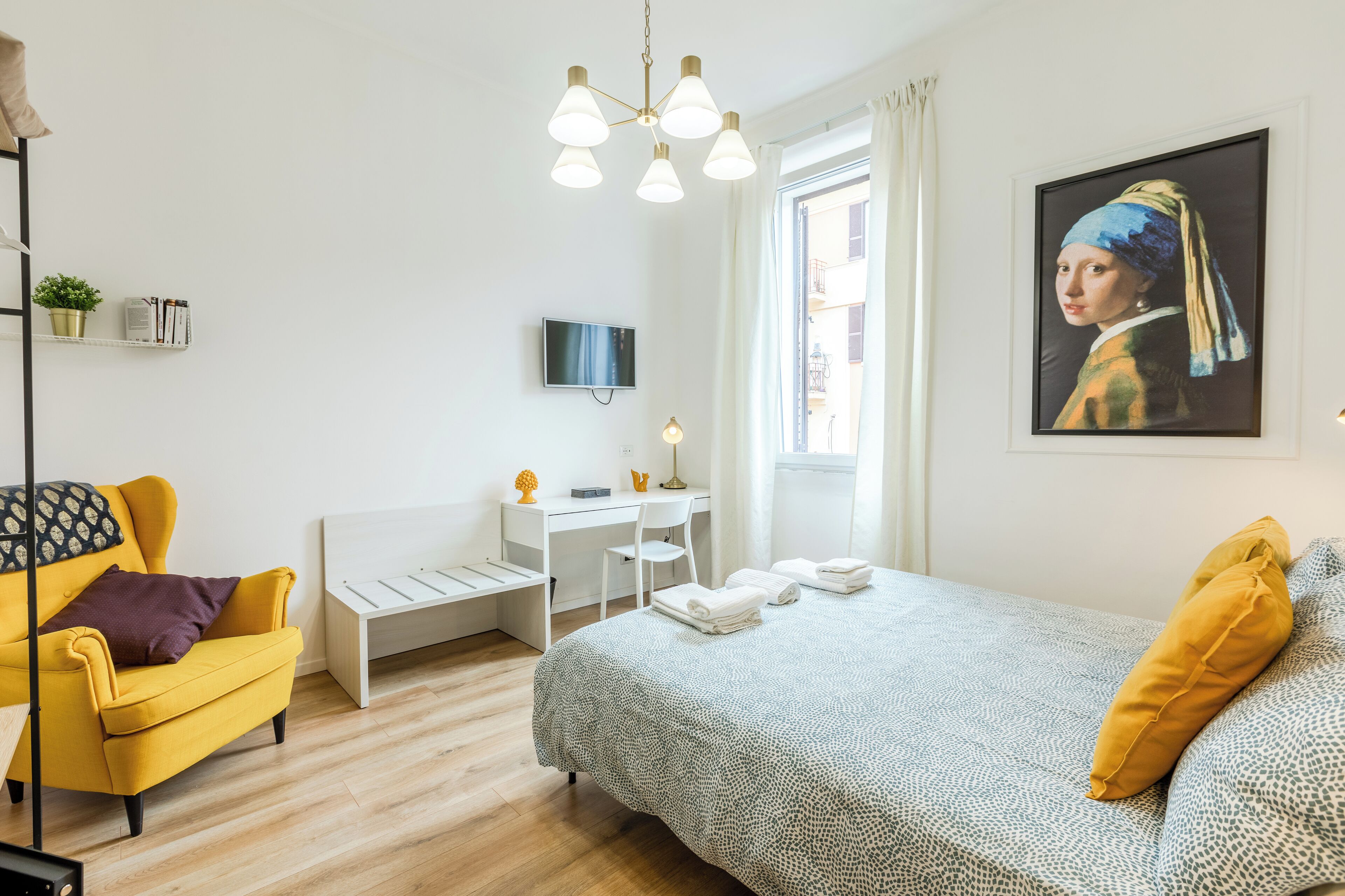 Een moderne hotelkamer met een bed, een bureau, een stoel en een televisie.