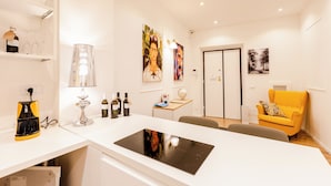 A modern kitchen with a built-in stove, wine bottles, glasses, and a yellow armchair. - Rome Lux House guest rooms (Rome)