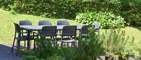 An outdoor seating area with a table and chairs, surrounded by greenery and plants.