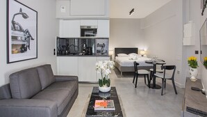 A compact living space with a sofa, a dining table with chairs, a bed, and a kitchen area. - Sublime Studio Center of Paris Montmartre (Paris)