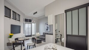 A modern hotel room with a bed, a dining area with a table and chairs, a sofa, and a large mirror. - Sublime Studio Center of Paris Montmartre (Paris)