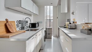 Una cucina moderna con mobili bianchi, un forno a microonde integrato e un frigorifero in acciaio inossidabile.