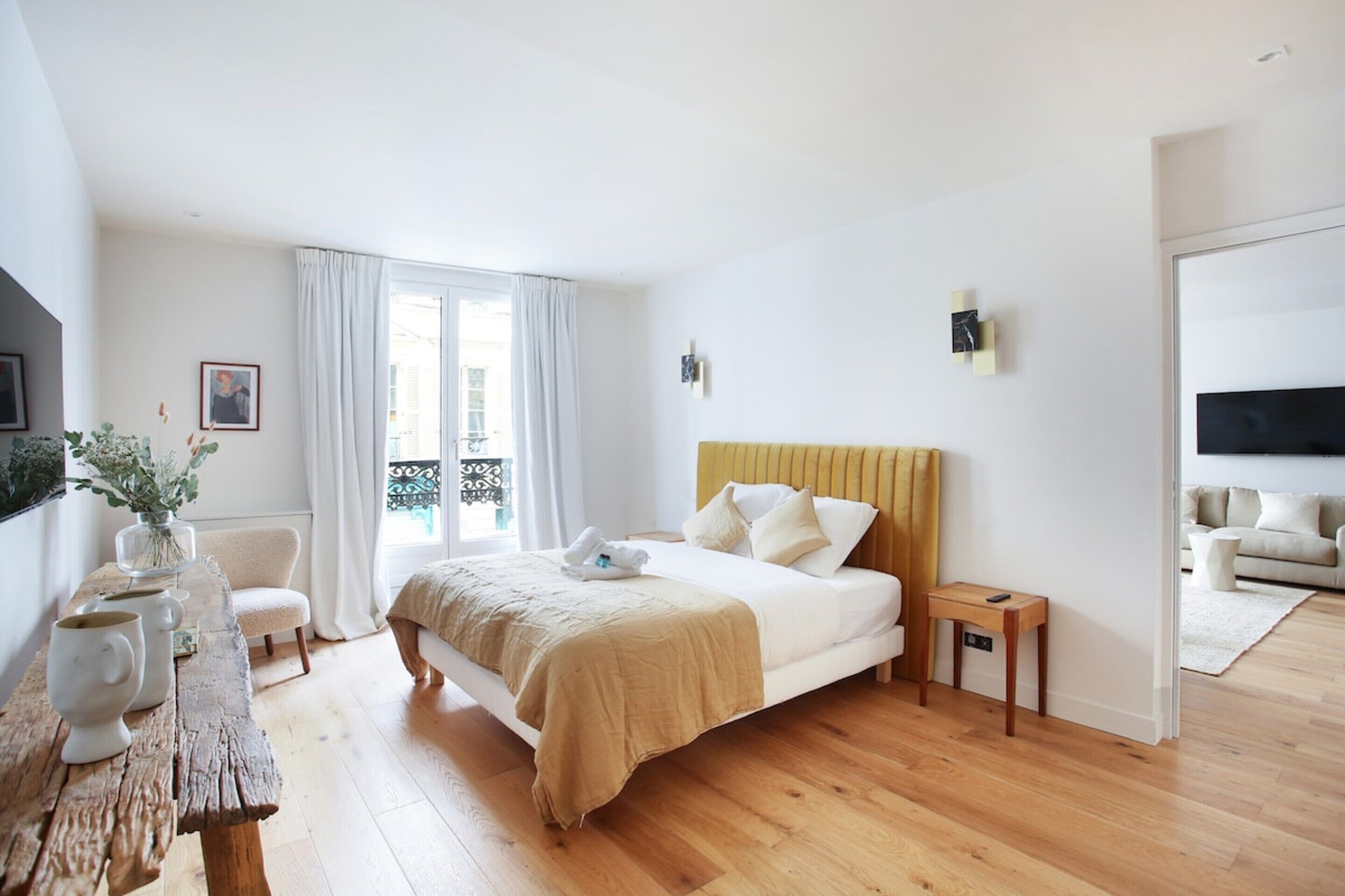 A bedroom with a bed, bedside table, and a window with curtains.