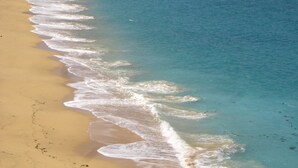 Une plage avec une eau d’un bleu limpide et un rivage sablonneux.