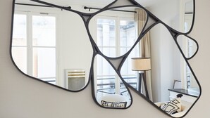 A room with a large mirror reflecting a balcony and a window.