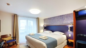 A hotel room with a bed, a chair, a desk, and a window with curtains. - Comfortable Studio - 2P - Republique (Paris)