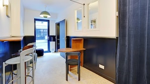 A modern kitchen with a wooden countertop, a built-in oven, and a black wall. There are two bar stools and a chair. - Comfortable Studio - 2P - Republique (Paris)