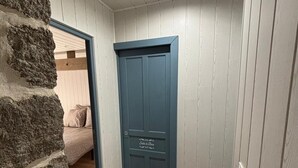Een kamer met een stenen muur, een houten vloer en een blauwe deur met een bordje.