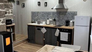 Een kleine keuken met een stenen muur, een magnetron, een fornuis, een spoelbak en een koelkast.
