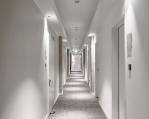 A long, narrow hotel corridor with white walls and doors on both sides. - Limehome Berlin Sybelstraße (Berlin)