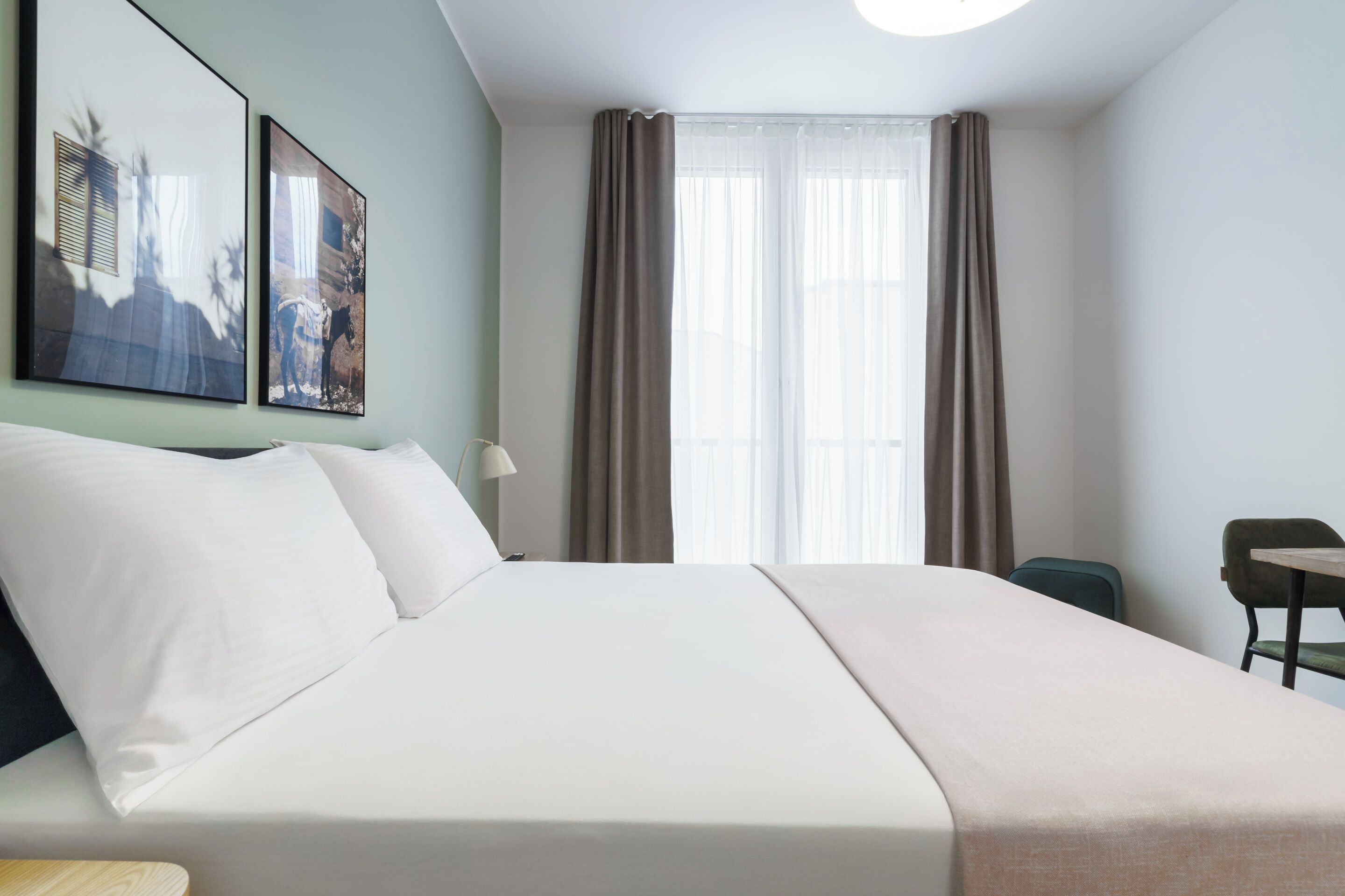 Una habitació d'hotel amb un llit gran, un escriptori i dos quadres penjats a la paret.