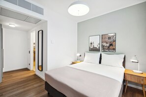 A modern hotel room with a large bed, bedside tables with lamps, a mirror, and two wall-mounted pictures. - Limehome Berlin Sybelstraße (Berlin)