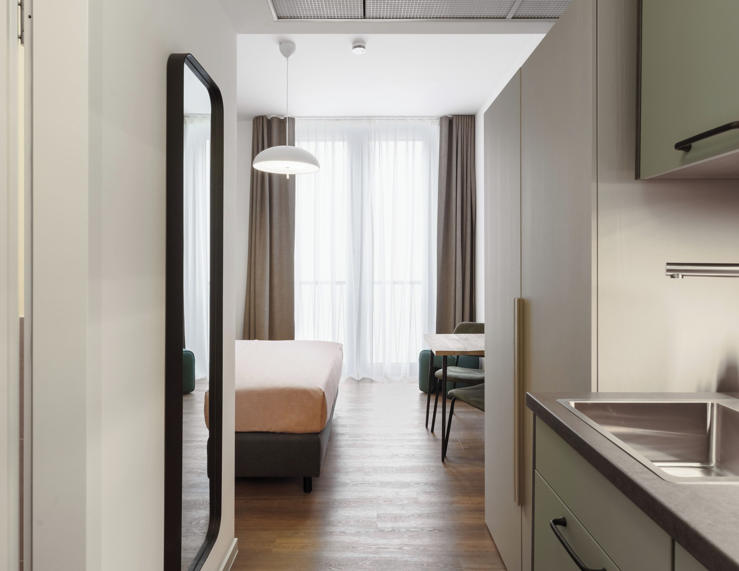 Ein modernes Hotelzimmer mit Bett, Essbereich und Küchenzeile.