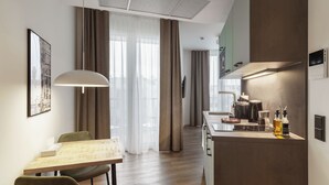 A modern kitchen with a dining area, featuring a table, chairs, and a pendant light. - Limehome Berlin Sybelstraße (Berlin)