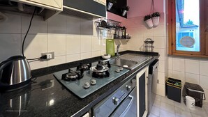 A modern kitchen with a gas stove, stainless steel appliances, and a window with a view of a building. - RED81 Suite - 10 min dal Duomo - 2 camere (Milan)
