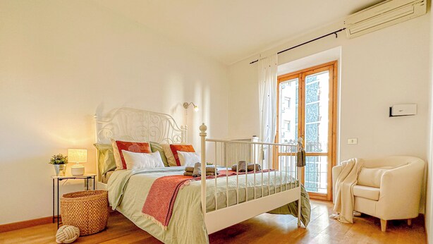 A bedroom with a bed, bedside table, lamp, and a chair. - RED81 Suite - 10 min dal Duomo - 2 camere (Milan)