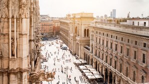 Una amplia plaza abierta flanqueada por edificios históricos, con arquitectura ornamentada y un espacio central para peatones.
