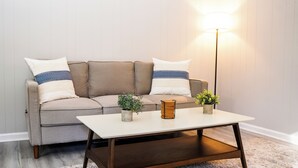 A modern living room with a beige sofa, two side tables, and a floor lamp.