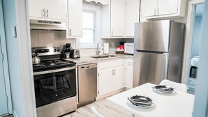 A modern kitchen with stainless steel appliances, white cabinetry, and a white countertop.