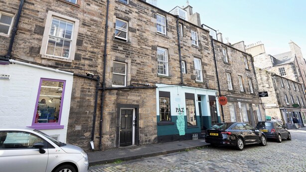 A stone building with multiple windows and a sign for 'Paz' on the ground floor. - Argyl | Charming 2-Bedroom Apt. on Thistle Street (Edinburgh)
