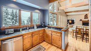Una cocina moderna con armarios de madera, encimeras de granito y un ventanal con vistas a un paisaje nevado.