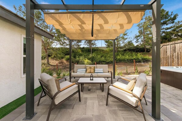 Un espacio de patio cubierto con un conjunto de sofá, dos sillas y una mesa.