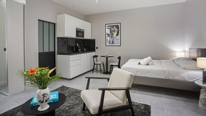 Una habitación de hotel moderna con cama, escritorio, silla, pequeña cocina y mesa de comedor.