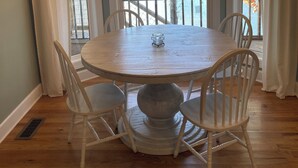 Een eethoek met een ronde tafel, witte stoelen en een kroonluchter.