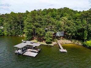 A lakeside property with a dock, a covered seating area, and a house surrounded by dense forest. - The retreat at Bay Pine Point, convenient to EVERYTHING Lake Martin and Auburn! (Jacksons' Gap)
