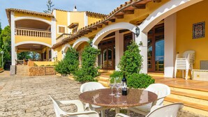 A courtyard with a round table, chairs, and a bottle of wine.
