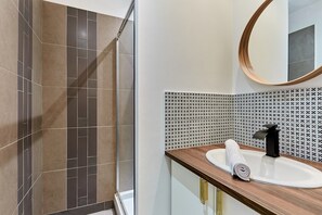 A modern bathroom with a shower, a sink with a wooden countertop, and a mirror with a wooden frame. - Charming 1 Bedroom Apartment Eiffel Tower (Paris)
