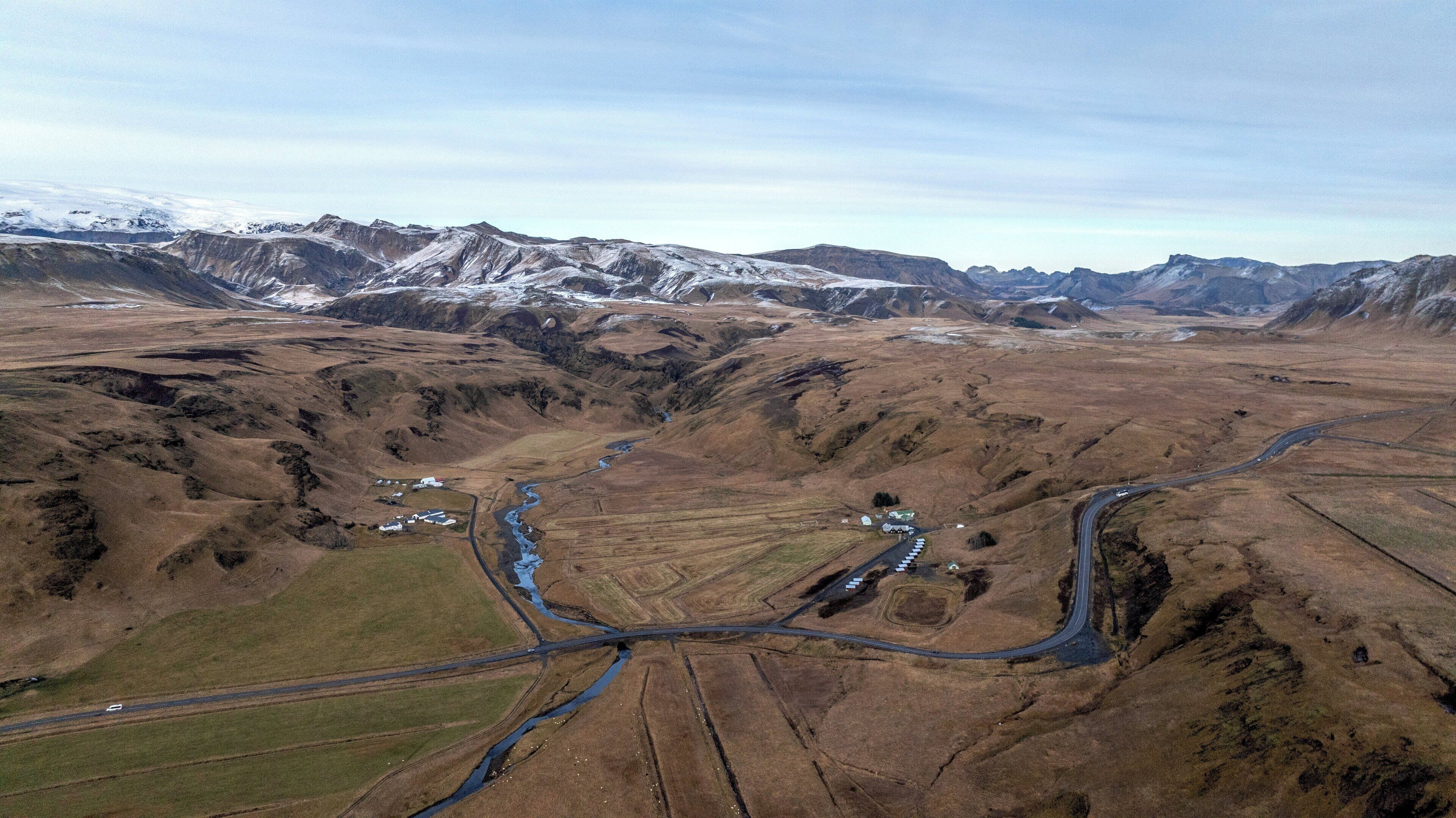 Vue aérienne d’une vallée avec une rivière, des routes et des bâtiments dispersés.