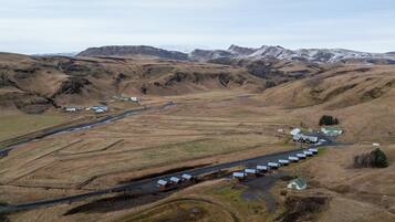 An aerial view of a rural area with a series of small buildings, a road, and a river.